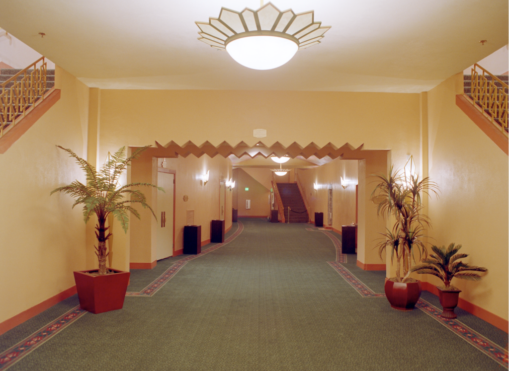 The downstairs or basement of fox theatre. Very antique look with the yellow walls, chandeliers and you can see the staircases leading up.